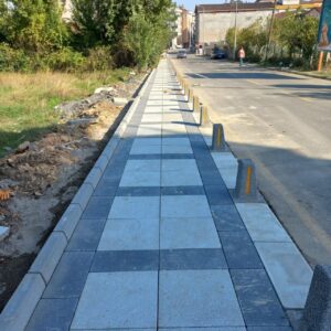 Beyaz renkli, kumlamalı yüzeye sahip kare şeklinde beton plaka taşı.
