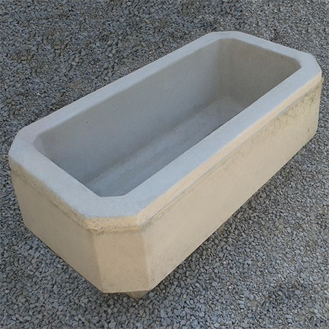 90x40x45 cm boyutlarında, doğal gri renkte beton malzemeden yapılmış, dikdörtgen formunda modern bir dış mekan saksısı. Saksı boş olup, iç kısmı doğal beton rengindedir. Saksının kenarları hafifçe pahlıdır ve dört köşesinde küçük ayaklar bulunmaktadır. Saksı, açık gri renkli çakıllı bir zeminin üzerinde durmaktadır. Ürün, dış mekan peyzaj ve güvenlik uygulamaları için uygundur.