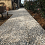 40x40x4 cm karışık renkli çakıllarla kaplanmış wash beton karoların palet stok görünümü ve dış mekan zemin uygulaması (dama deseni, bahçe yolu).