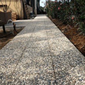 40x40x4 cm karışık renkli çakıllarla kaplanmış wash beton karoların palet stok görünümü ve dış mekan zemin uygulaması (dama deseni, bahçe yolu).