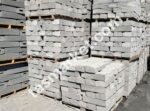 İnşaat alanında paletler üzerinde istiflenmiş gri renkli eğimli beton bordür taşları