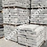 İnşaat alanında paletler üzerinde istiflenmiş gri renkli eğimli beton bordür taşları