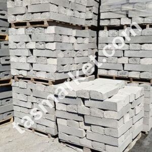 İnşaat alanında paletler üzerinde istiflenmiş gri renkli eğimli beton bordür taşları