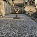 Wash beton karolarla kaplanmış, ortasında ağaç bulunan modern peyzaj zemin uygulaması. Gri ve beyaz doğal çakıl görünümlü karolar.
