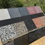 Beyaz çakıl, kırmızı çakıl, siyah agrega ve düz renkli wash beton karoların farklı modellerini gösteren dış mekan numune panosu.