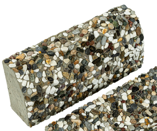 Yüzeyinde karışık renkli doğal çakılların belirgin olduğu, dikdörtgen formlu wash beton bordür taşının yakın çekim görüntüsü.