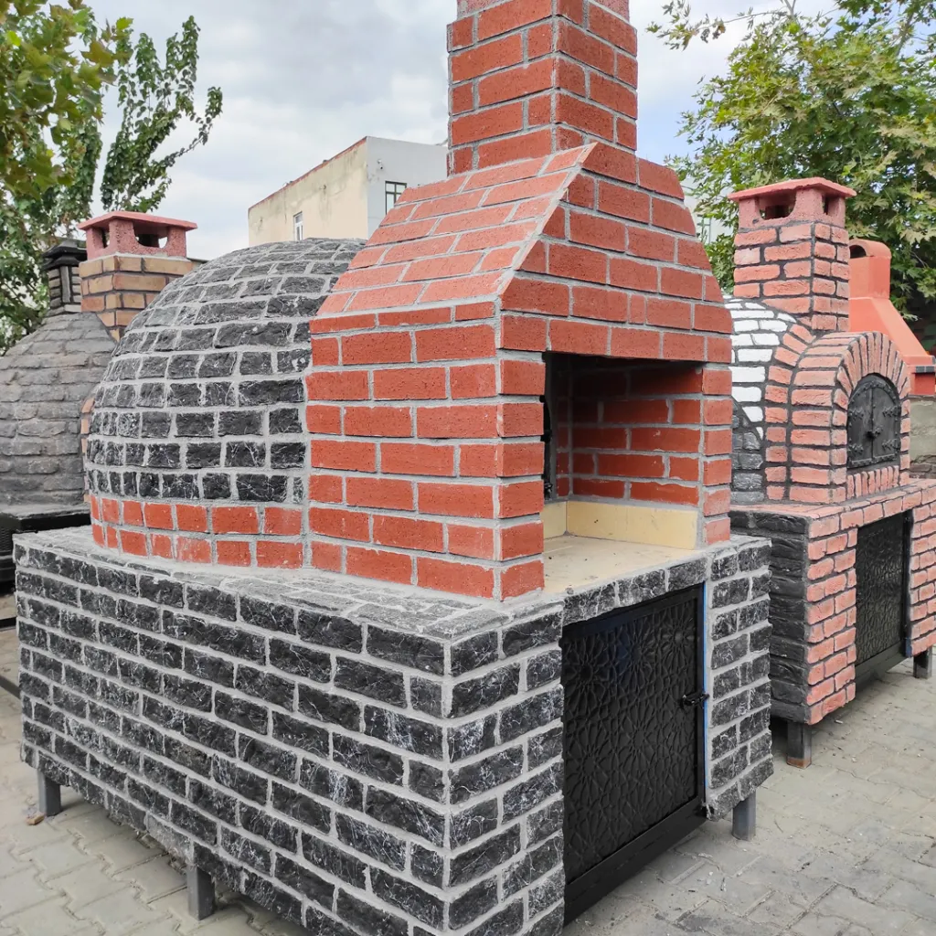 Palet üzerinde tekerlekli, doğal kayrak taşlarıyla kaplanmış, metal kapaklı ve krom bacalı seyyar taş fırın.