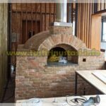 Doğal kayrak taşlarıyla kaplanmış, siyah metal kapaklı ve paslanmaz çelik bacalı hazır seyyar taş fırın. Malzeme kalitesini gösteren örnek model.