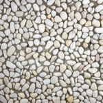 Çok renkli doğal çakıl agregalı wash beton karolarla kaplanmış, ortasında ağaç bulunan modern bahçe zemin uygulaması ve bina girişi.