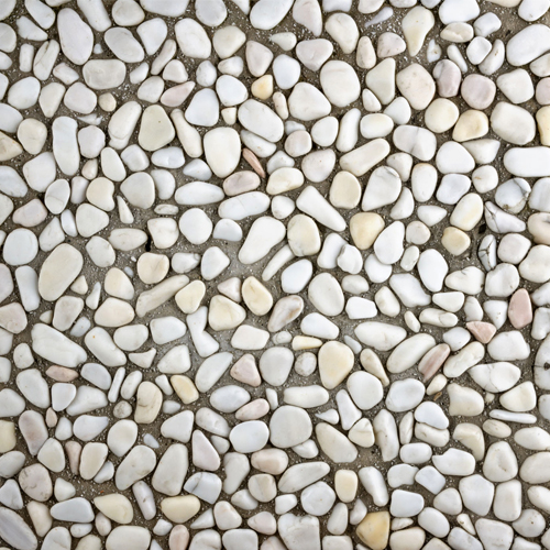 Çok renkli doğal çakıl agregalı wash beton karolarla kaplanmış, ortasında ağaç bulunan modern bahçe zemin uygulaması ve bina girişi.