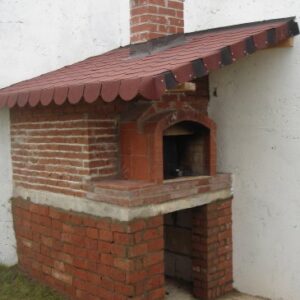 Kırmızı tuğla ile örülmüş, kemerli fırın ağzı ve kiremit desenli shingle çatısı olan geleneksel bahçe fırını. Alt kısımda odunluk bölmesi.