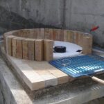 Beton kaide üzerinde refrakter ateş tuğlaları ile fırın kubbesinin ilk sırasının örülme aşaması. Ortada strafor kalıp ve yanda barbekü ızgarası.