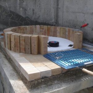 Beton kaide üzerinde refrakter ateş tuğlaları ile fırın kubbesinin ilk sırasının örülme aşaması. Ortada strafor kalıp ve yanda barbekü ızgarası.