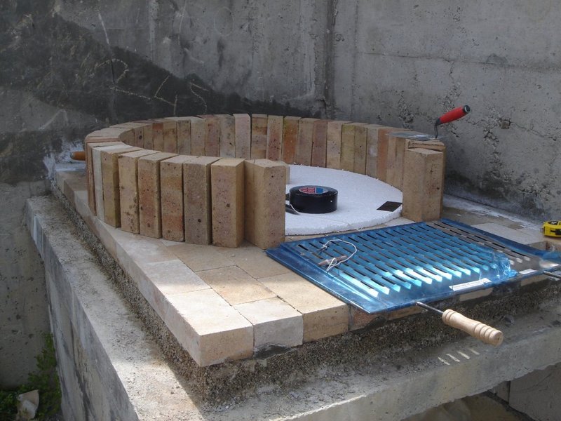 Beton kaide üzerinde refrakter ateş tuğlaları ile fırın kubbesinin ilk sırasının örülme aşaması. Ortada strafor kalıp ve yanda barbekü ızgarası.