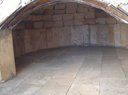 Kırmızı tuğladan kaidesi ve odunluğu örülmüş, kırmızı sıvalı kubbesi ve uzun tuğla bacası olan modern bahçe fırını.