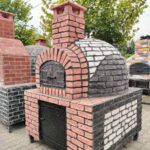 Beyaz sıva ile kaplanmış, tuğla kemerli fırın ve entegre barbekü/ocak gözü içeren modern dış mekan mutfağı.