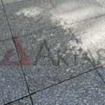 Siyah veya koyu gri çakılların baskın olduğu, güneş ışığı yansımasıyla parlak görünen wash beton karoların zemin uygulaması.