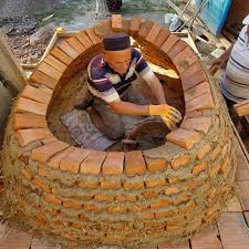 Geleneksel kıyafetli bir usta, harç ve tuğla kullanarak fırın kubbesini el emeği ile örme işlemi sırasında görülüyor.