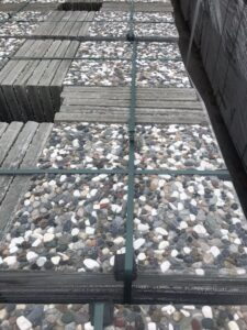 Farklı renkli doğal çakıl agregalı, palet üzerinde istiflenmiş wash beton karolar.