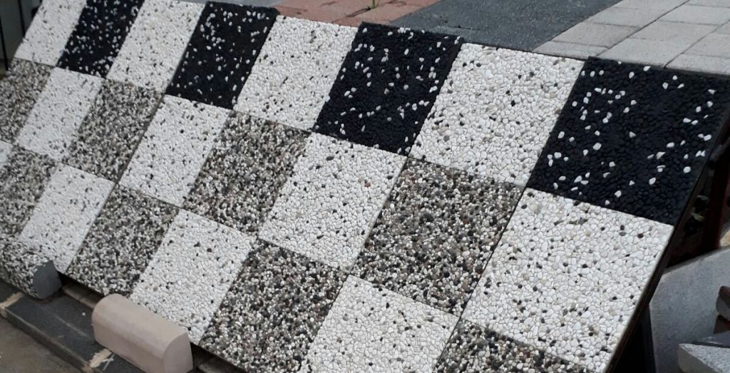 Farklı renk ve desenlerde wash beton karo numuneleri, dama desenli karo uygulaması ve doğal peyzaj alanında kullanılmış wash beton zemin.