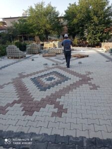 Gri ve kırmızı kilitli parke taşlarıyla desenli döşeme yapılan bahçe zemin uygulaması, İzmir.