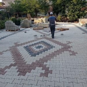 Gri ve kırmızı kilitli parke taşlarıyla desenli döşeme yapılan bahçe zemin uygulaması, İzmir.