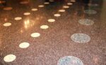 Koyu kahverengi/siyah zeminde beyaz, dairesel mozaik desenleri bulunan, yüksek parlaklıkta cilalanmış terrazzo (dökme mozaik) zemin.
