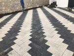 Siyah ve beyaz renklerde, balıksırtı (zikzak) deseninde döşenmiş dikdörtgen prizma parke taşı zemin kaplaması.