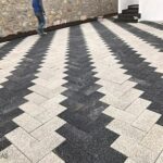 Siyah ve beyaz renklerde, balıksırtı (zikzak) deseninde döşenmiş dikdörtgen prizma parke taşı zemin kaplaması.