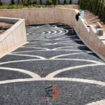 Siyah ve beyaz/açık renkli doğal küp taşlardan yapılmış, dairesel dalga motifli, lüks araç yolu zemin kaplaması.