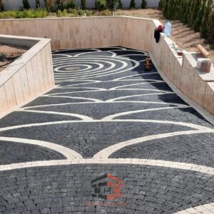 Siyah ve beyaz/açık renkli doğal küp taşlardan yapılmış, dairesel dalga motifli, lüks araç yolu zemin kaplaması.