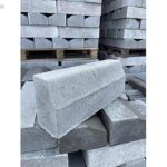 Kaldırım kenarı için kullanılan eğimli gri beton bordür taşları istifi