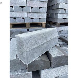 Kaldırım kenarı için kullanılan eğimli gri beton bordür taşları istifi