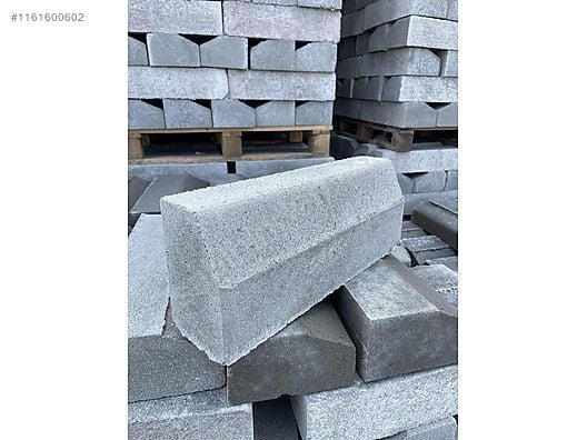 Kaldırım kenarı için kullanılan eğimli gri beton bordür taşları istifi