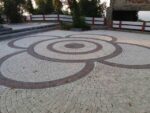 Açık renkli begonit zeminde koyu ve kırmızı bantlı dairesel meydan deseni