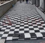 Dar dış mekân geçişinde siyah ve beyaz kare taşlarla oluşturulmuş dama deseni