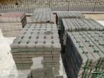 Yeşil çemberlerle sabitlenmiş paletlerde gri ve kırmızı beton kilit taşları
