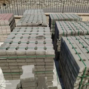 Yeşil çemberlerle sabitlenmiş paletlerde gri ve kırmızı beton kilit taşları