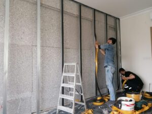 İç duvar önünde levha ve metal profillerle yalıtım uygulaması yapan ekip