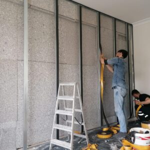 İç duvar önünde levha ve metal profillerle yalıtım uygulaması yapan ekip