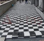 Siyah ve beyaz kare parke taşlarıyla dama deseninde döşenmiş dış mekân yürüyüş yolu