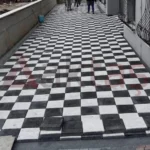Siyah ve beyaz kare parke taşlarıyla dama deseninde döşenmiş dış mekân yürüyüş yolu