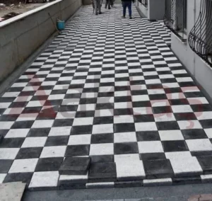 Siyah ve beyaz kare parke taşlarıyla dama deseninde döşenmiş dış mekân yürüyüş yolu