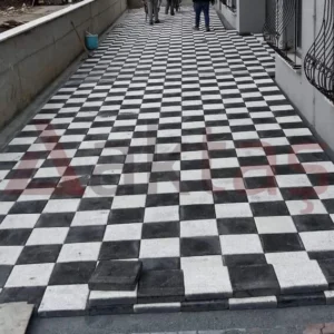 Siyah ve beyaz kare parke taşlarıyla dama deseninde döşenmiş dış mekân yürüyüş yolu